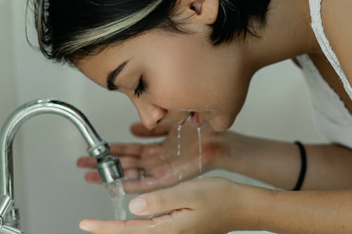 A woman washing her face with tea tree oil solution