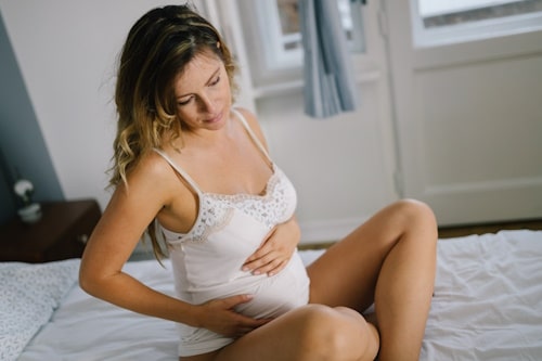 Woman on bed experiencing pregnancy hormones