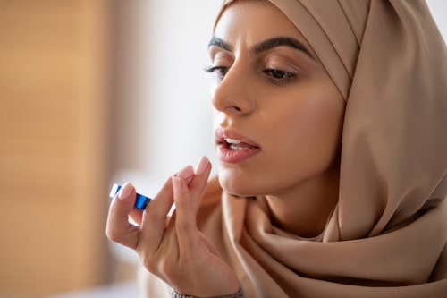 Side view image of woman putting lip product