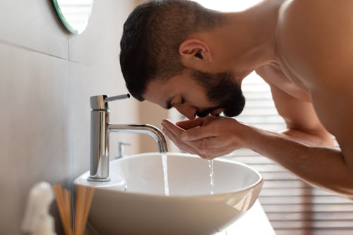 Man washing his face with warm water before shaving