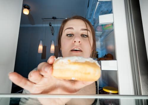 Woman taking donut from refrigirator