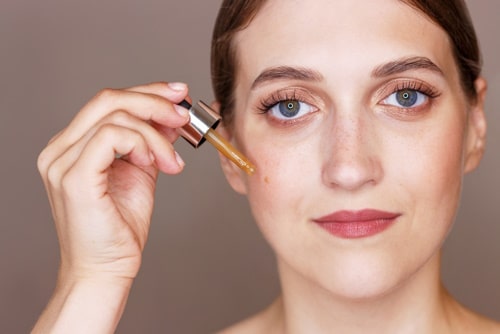 Portrait of young woman holding dropper with vitamin e 