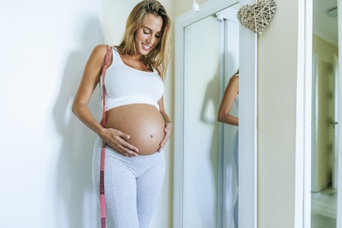 Pregnant mother checking herself with a body mirror