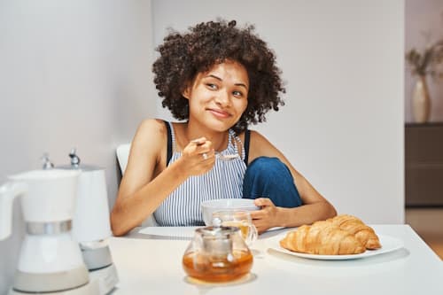 Woman sitting on table eating oatmeal