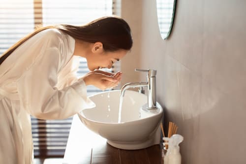 Woman washing her face on a sink