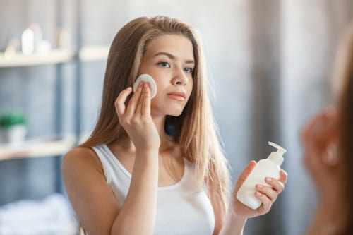 Woman using coconut oil to remove makeup