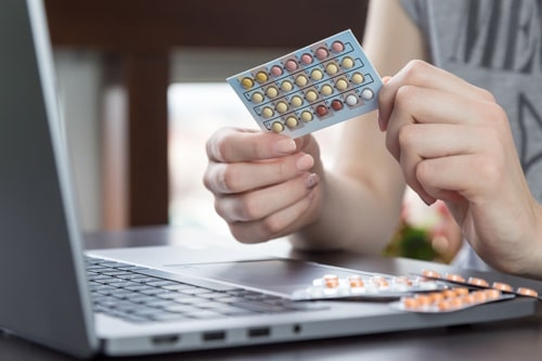 Woman looking at her birth control pills