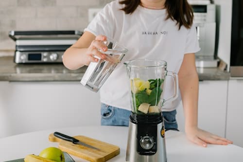 Woman preparing detox drink with blender