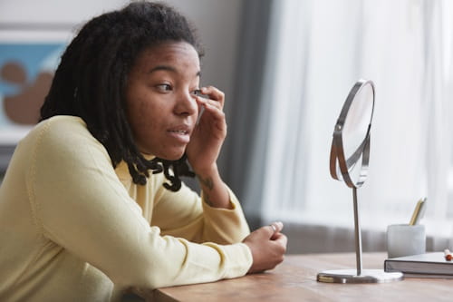 African American woman looking at her face on a mirror