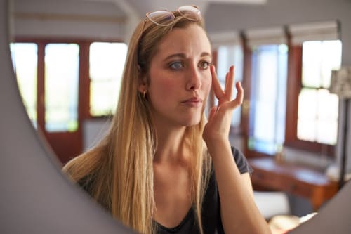 Caucasian woman checking her face on the mirror