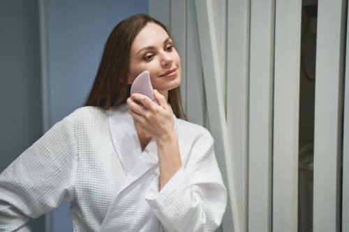 Woman using skin care scrub to exfoliate face