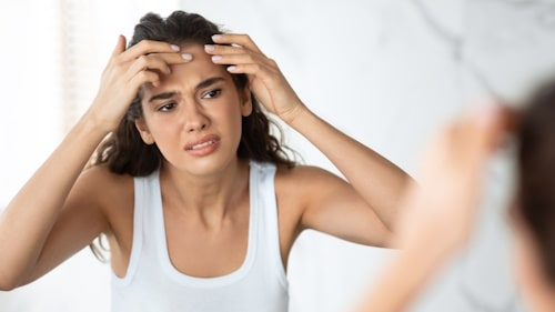 Woman with acne trying to squeeze pimple