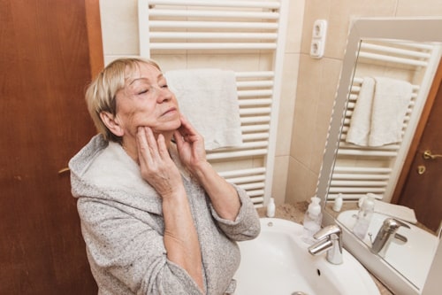 Woman in bathrobe touching her soft face