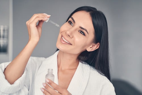 Woman putting squalane oil on face