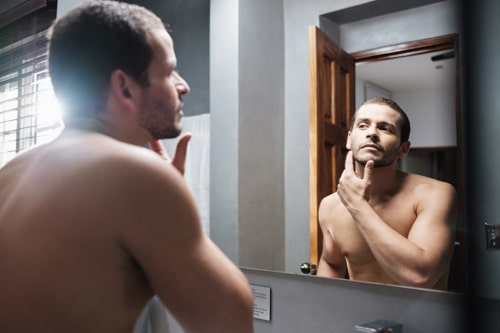 Muscualr man checking his face for acne