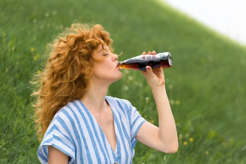Side view of beautiful redhead woman drinking diet soda 