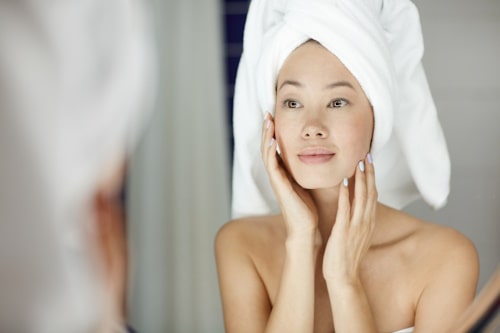 Woman looking at her face with mirror