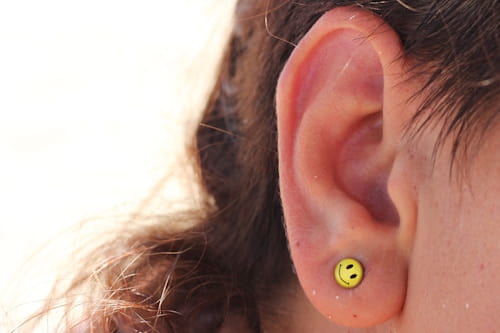 Close up of female ears with smiley earings