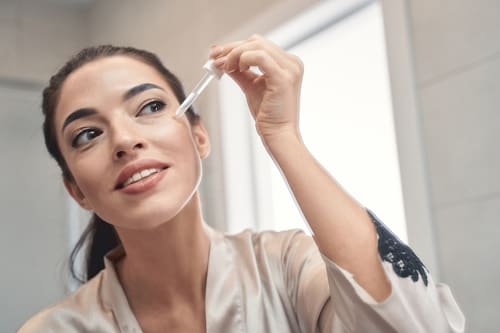 Beautiful woman using serum on her face