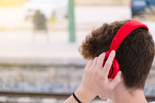 Teen boy with curly hair putting on red headphones