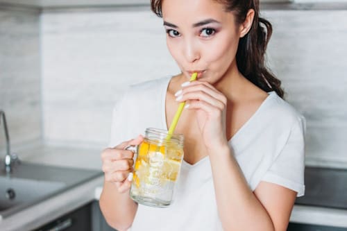 Woman drinking lemon water using a straw