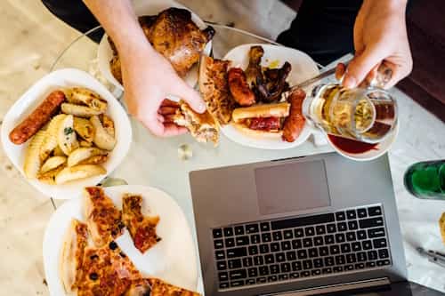 Top view of person eating greasy food with laptop