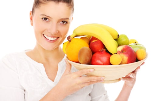 Woman holding basket of fruits near her face