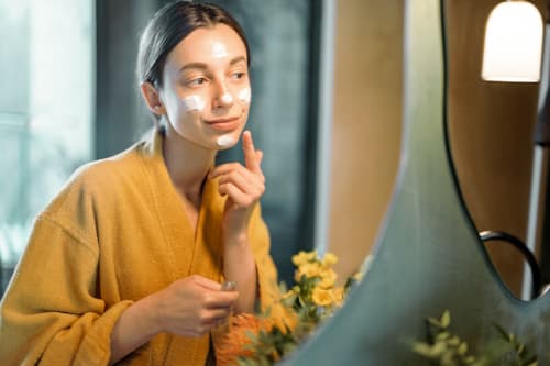 Woman wearing yellow applying sun block on her face