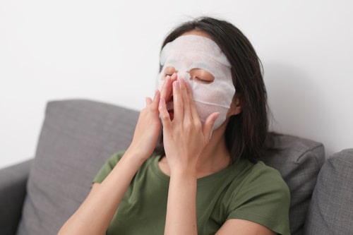 Girl sitting on a sofa while wearing face mask