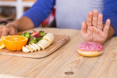 Woman choosing healthy food over donut