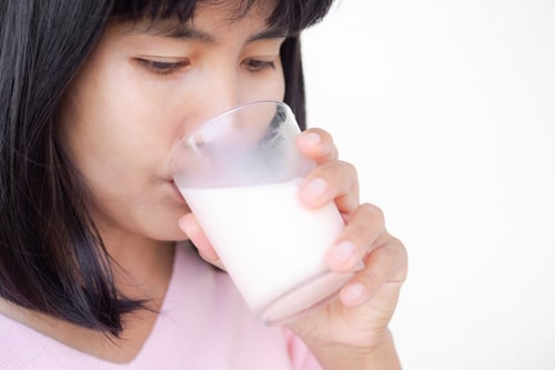 Woman drinking milk from glass close up 