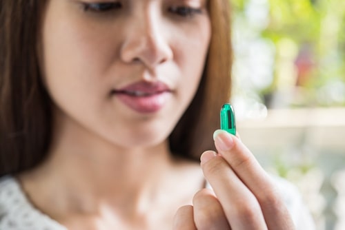 Woman holding green liquid capsule