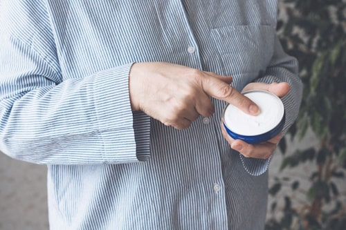 Woman in a blue shirt smears hands with vicks vaporub