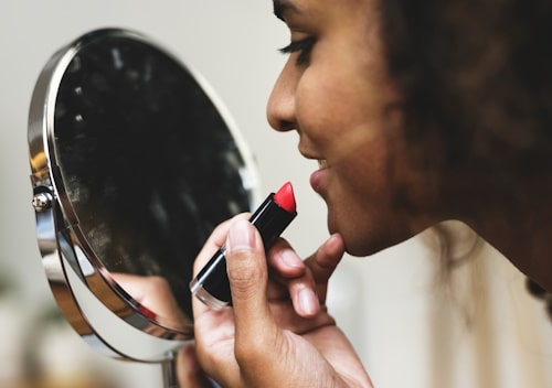 Woman putting on lipstick