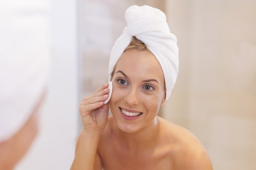 Happy woman exfoliating her face during skin care