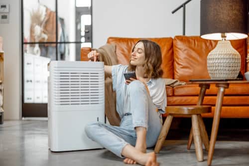 Woman sitting beside a large dehumidifier