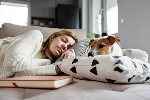 Woman resting on sofa with dog