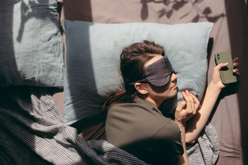 Woman sleeps during the day with a mask over her eyes