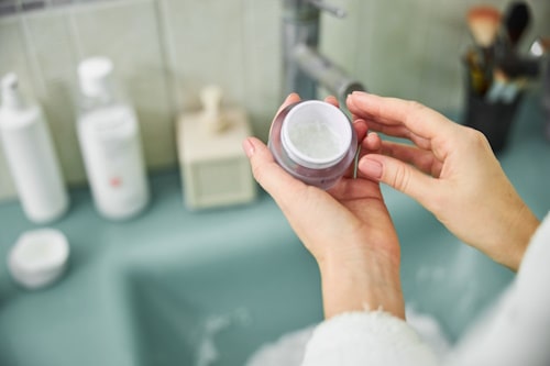 Face cream on hands of woman