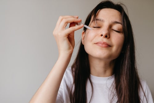 Young woman using a dropper on her face