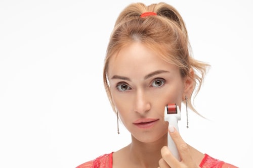 Woman using microneedling tool on her face