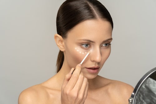 Woman applying concelaer on her face
