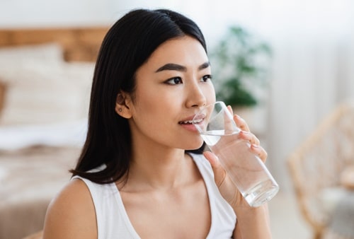 Young asian girl drinking water at bedroom at home 