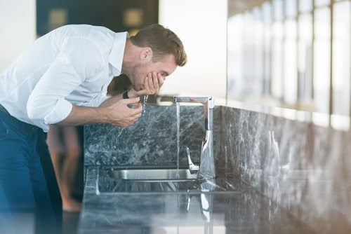 Man in suit washing his face after crying