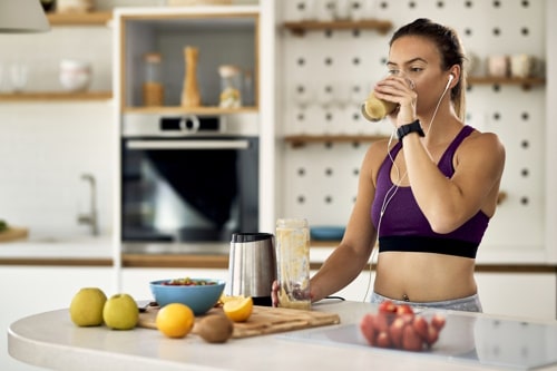Young female athlete drinking fruit smoothie after workout