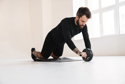 Man with beard exercising with push up wheels