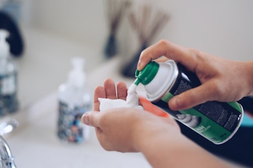 Young man is squeezing shaving cream onto the palm 