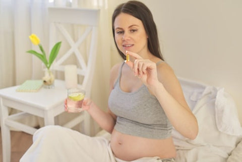Pregnant woman holding multivitamin pill