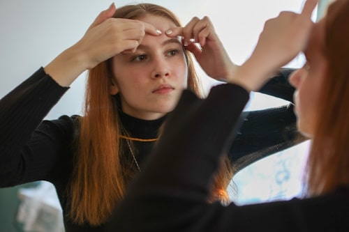 Young teen girl picking on her pimple