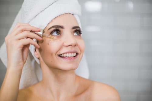 Woman using dropper to put serum on face